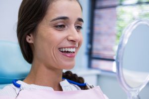 Patient smiling while looking at mirror in dental clinic