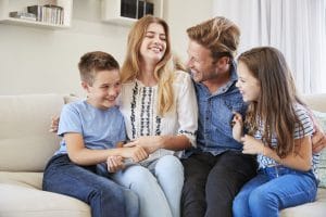 Smiling Family Relaxing On Sofa At Home Together